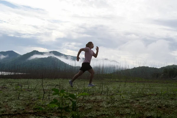 Asian women run in the countryside by the river in the morning. fitness woman running in the forest. Sports and recreation healthy lifestyle concept.