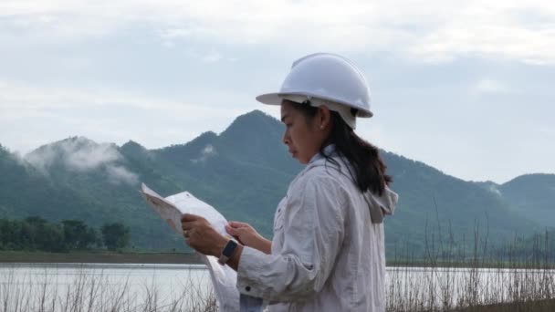 Engineering Ecologist Woman Helmet Holding Map Stands Bank River Develop — Vídeo de stock
