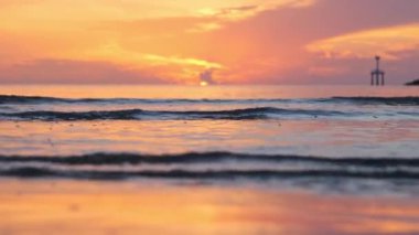 Beautiful sunset view on the beach. Colorful sea beach sunset with golden light reflected on the water surface and soft waves. Summer vacation and travel concept.