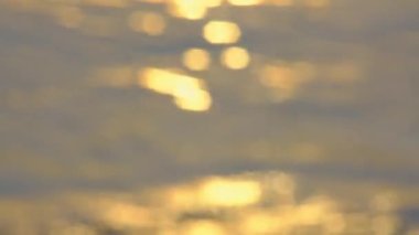 Bokeh background of colorful sea beach sunset with golden light reflecting on water surface and soft waves. Summer vacation and travel concept.