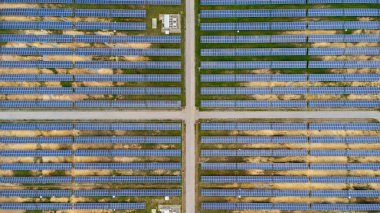 Aerial view of solar power plant on green field. Solar panels system for solar power generation. Green energy for sustainable development to prevent climate change and global warming to protect earth.