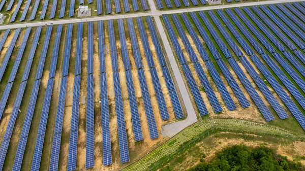 Aerial view of solar power plant on green field. Solar panels system for solar power generation. Green energy for sustainable development to prevent climate change and global warming to protect earth.