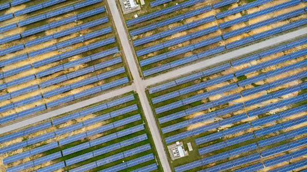 Aerial view of solar power plant on green field. Solar panels system for solar power generation. Green energy for sustainable development to prevent climate change and global warming to protect earth.