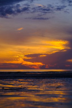 Beautiful sunset view on the beach. Colorful sea beach sunset with golden light reflected on the water surface and soft waves. Summer vacation and travel concept.