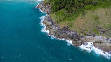 Mavi okyanustaki kayalıklara çarpan deniz dalgalarının hava görüntüsü. Phuket Okyanusu 'ndaki en yüksek kıyı kayaları manzarası. Sabahları Laem Phromthep Pelerini 'nin manzara manzarası.