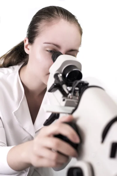 Mulher jovem olhando através do microscópio — Fotografia de Stock