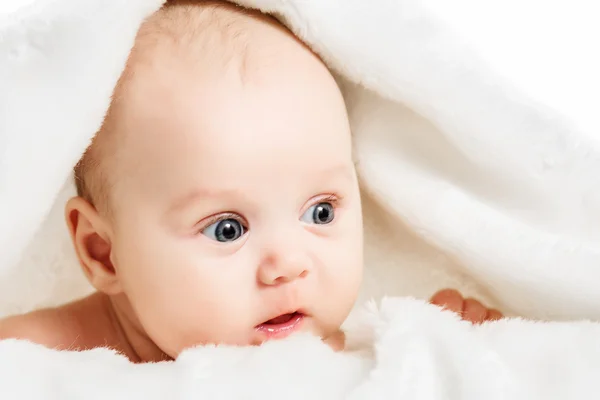 Baby girl is hiding under the white blanket — Stock Photo, Image