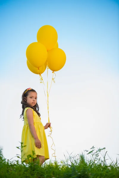 Happy girl with yellow balloons — Stock Photo, Image