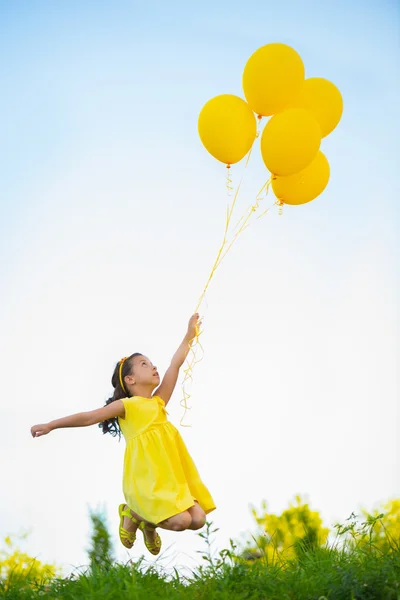 Menina feliz com balões amarelos — Fotografia de Stock