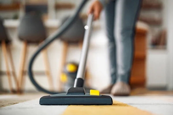 家の中でカーペットを掃除しながら掃除機を使う女 — ストック写真
