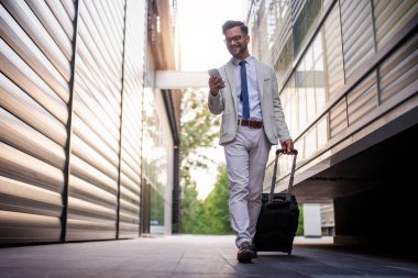 Young man on business trip walking with his luggage,drink coffee to go.