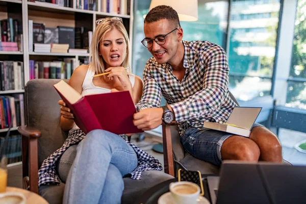 Eğitim, insanlar, üniversite, yaşam tarzı konsepti. Birkaç uluslararası öğrenci kütüphanede birlikte okuyor..