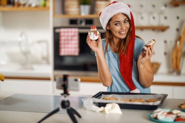 Mutfakta kamera kullanıp video kaydeden bir kadın. Genç bir kadın Noel kurabiyesi yapıyor..