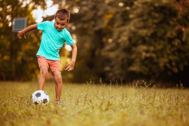 Parkta futbol oynayan genç bir çocuk. Futbol ile aksiyon. Çocuklar futbol..