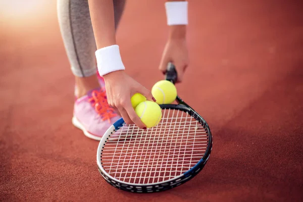 Close up on racket and ball in hand of tennis player.