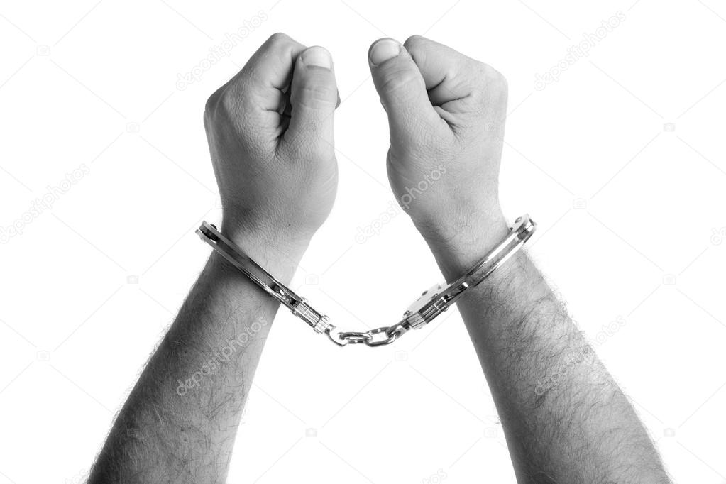 closeup of the hands of a man with handcuffs in black and white
