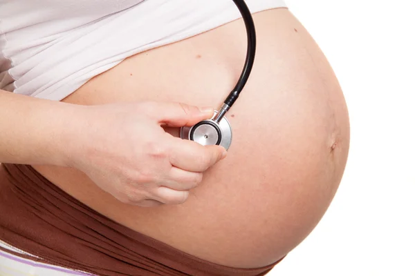 Pregnant woman listening her belly with stethoscope — Stock Photo, Image