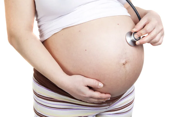 Pregnant woman listening her belly with stethoscope — Stock Photo, Image