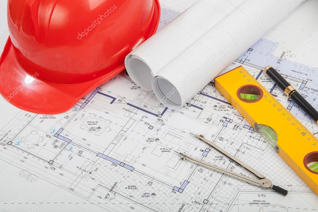 Red helmet, construction drafts and tools on the table