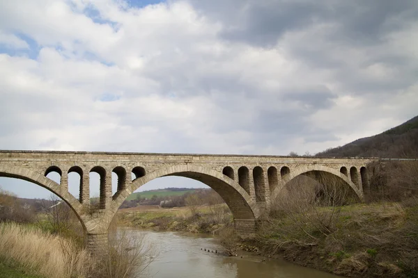 Old stone middle age bridge in Bulgaria, against a cloudy sky — Stock Photo, Image