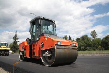 Large road-roller paving a road. Road construction clipart