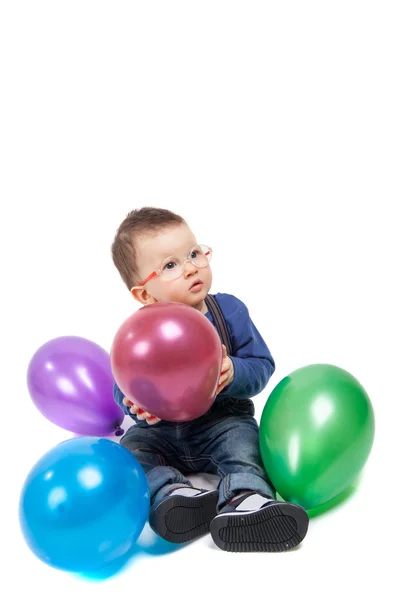 Niño pequeño con anteojos jugando con globos de colores — Foto de Stock