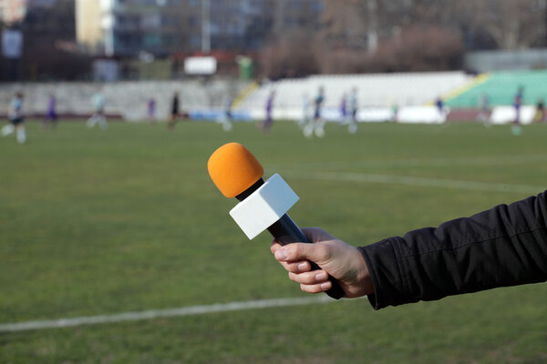 hand holding microphone for interview during a football mach