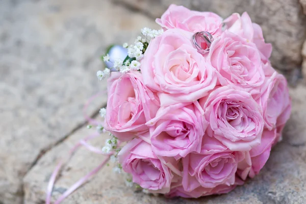 Zilveren bruiloft ringen op bruiloft boeket van roze rozen — Stockfoto