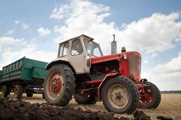 Alter Traktor im Feld, vor bewölktem Himmel — Stockfoto
