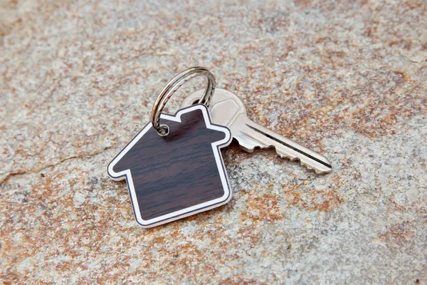 Close up of house shaped keychain and key — Stock Photo, Image