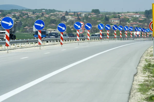 Road with a lot of road signs showing directions — Stock Photo, Image