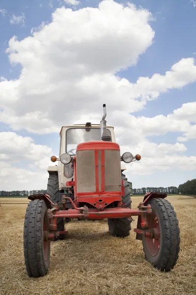 Vieux tracteur dans le champ, contre un ciel nuageux — Photo