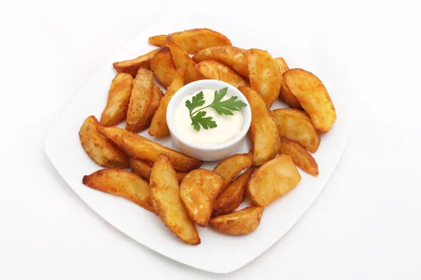 Fried potato wedges with white sauce on white plate — Stock Photo, Image