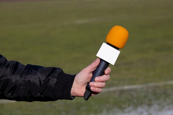 Microfone de mão segura para entrevista durante um mach de futebol — Fotografia de Stock