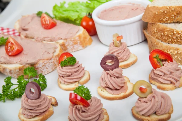 Partij schotel met sneetjes brood met huisgemaakte pate, versierd met groenten — Stockfoto