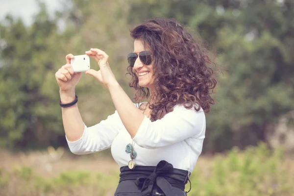 Young smiling woman taking picture with a smart phone — Stock Photo, Image