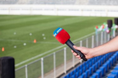 hand holding microphone for interview during a football mach clipart