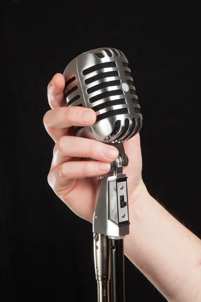 Retro bir mikrofon siyah arka plan üzerinde tutan el — Stok fotoğraf