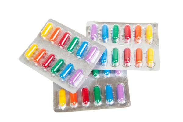 Muchas píldoras coloridas en paquetes de ampollas, aisladas en blanco — Foto de Stock