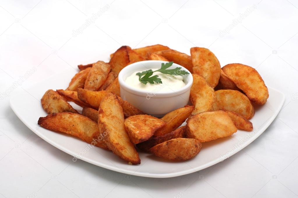 Fried potato wedges with white sauce on white plate