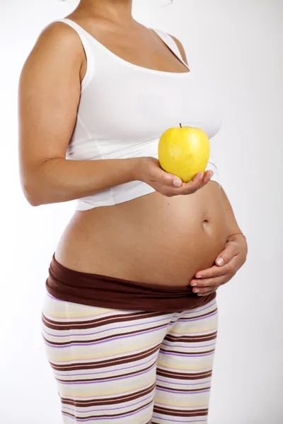 Беременная женщина держит яблоко — стоковое фото