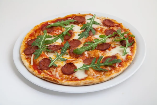 Pizza with salami, cheese and arugula on white plate — Stock Photo, Image