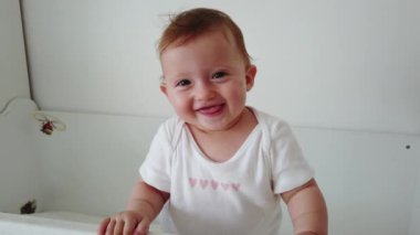 Sevimli bebek gülüyor ve eğleniyor, beşiğinde duruyor. Mutlu bebek. Bebek duyguları. Bebek gülümsemesi.