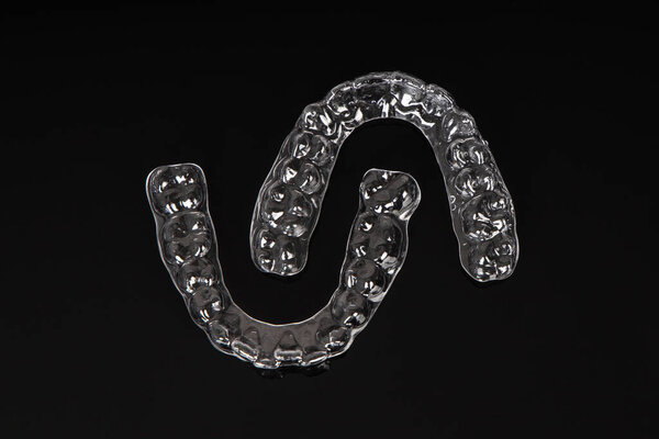 Invisible orthodontics cosmetic brackets on black background. Tooth aligners, for beautiful smile.