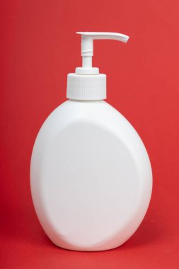 Kırmızı arka planda beyaz markasız şeker şişesi. Sıvı sabunla plastik şişe.