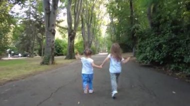 Parkta koşan iki küçük kız. Mutlu kız kardeşler, eğleniyorlar. Aile aktivitesi açık havada.