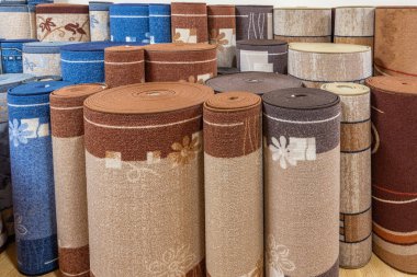 Mağazada bir sürü renkli halı var. Çeşitli halılar sarılmış