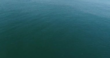 İnsansız hava aracı okyanus ve deniz üzerinde uçuyor. Suya yakın.