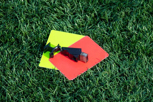 緑の芝生の上でサッカー サッカーゲーム笛 赤と黄色のカードを参照してください 2枚のペナルティカードと審判Fの笛 — ストック写真