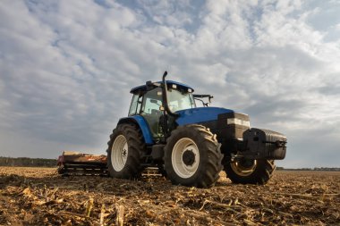 Büyük mavi modern traktör sahada. Hasattan sonra toprağı işlemek 